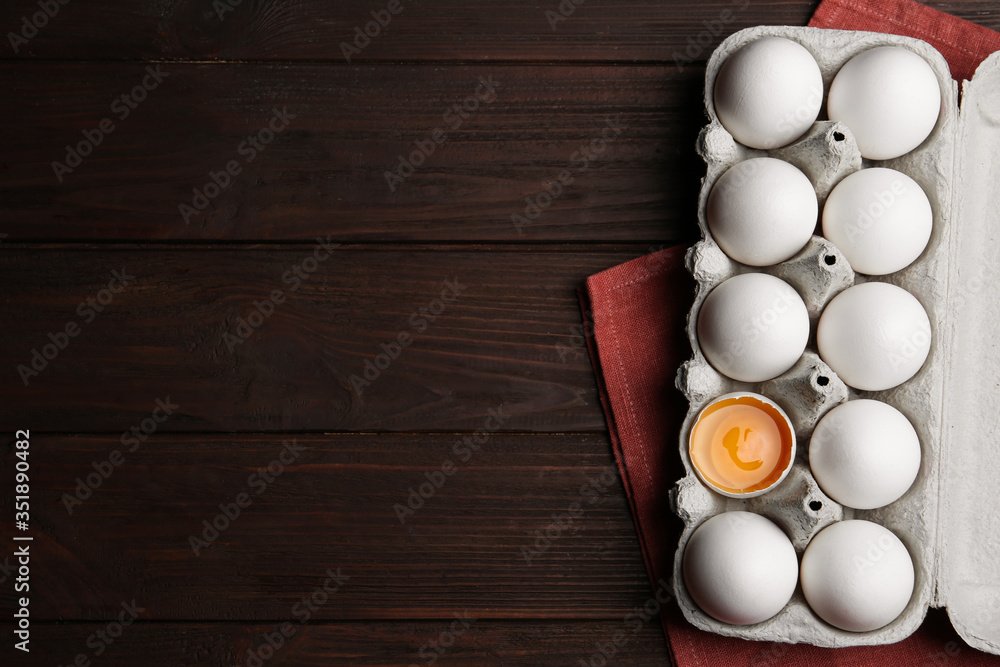 Fresh raw chicken eggs in box on wooden table, flat lay. Space for text Fresh raw chicken eggs in box on wooden table, flat lay. Space for text