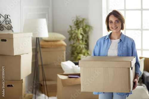Portrait of pretty woman holding a box at new home