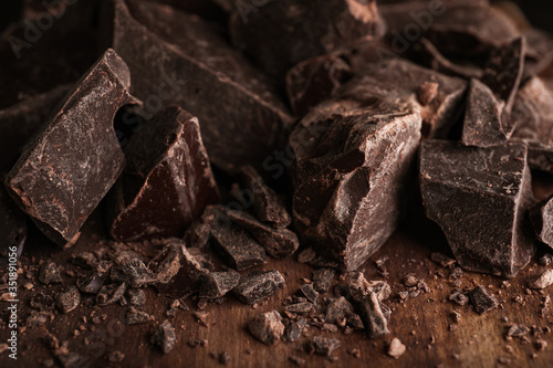 Pieces of dark chocolate on wooden table, closeup