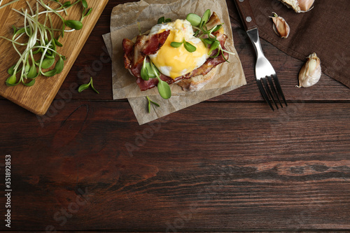 Delicious egg Benedict served on wooden table, flat lay. Space for text