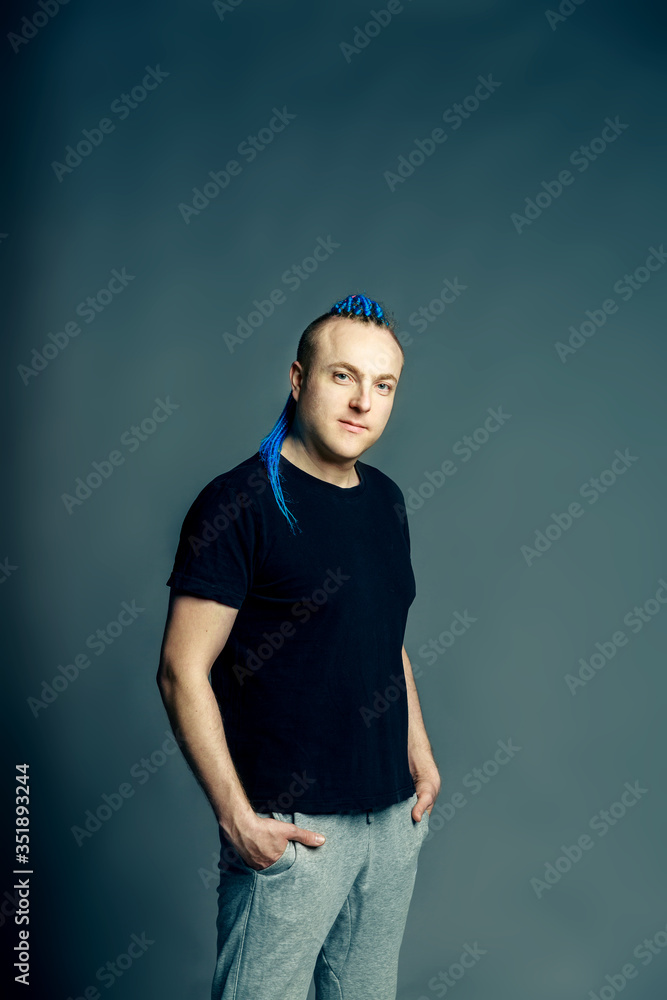 A man with a braided mohawk haircut calmly posing holding hands in pockets of sweatpants A man with a braided mohawk haircut calmly posing holding hands in pockets of sweatpants