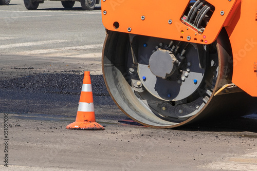 Urban road construction, asphalt paver. A compactor machine for laying new asphalt. © Andrey