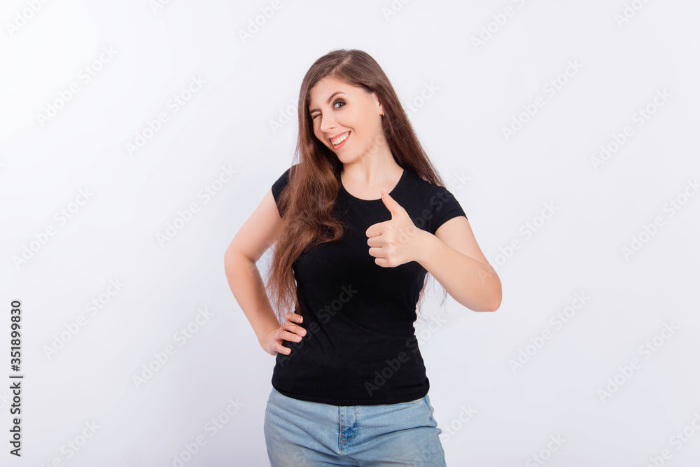 Smiling girl in a black t-shirt shows thumb up isolated on a white background. Young woman makes a gesture i like it, great job. Language of the body. Smiling girl in a black t-shirt shows thumb up isolated on a white background. Young woman makes a gesture i like it, great job. Language of the body.