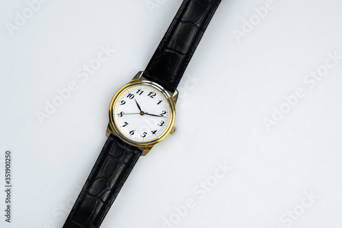 Retro golden wristwatch with Roman numerals and croco leather belt isolated close up on white background.