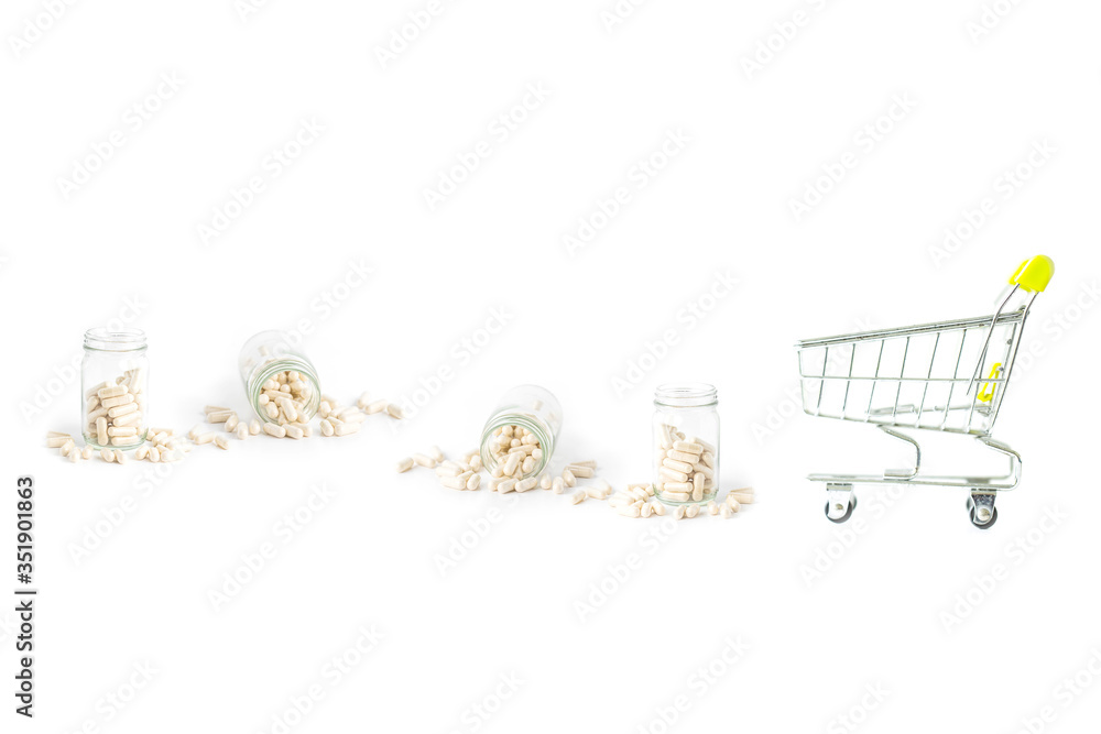 shopping cart with herb capsule pills spilling out off bottle isolated on white background.Image for Medical Concept.