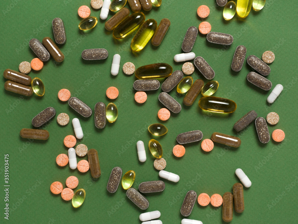 Different colorful dietary supplements on green background. Different colorful dietary supplements on green background.