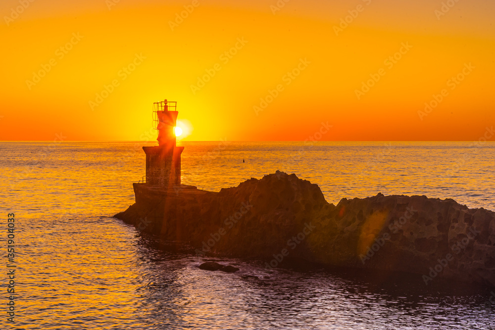 Detail of the sun behind the lighthouse in the orange sunset of the town of Pasajes San Juan. Gipuzkoa, Basque Country