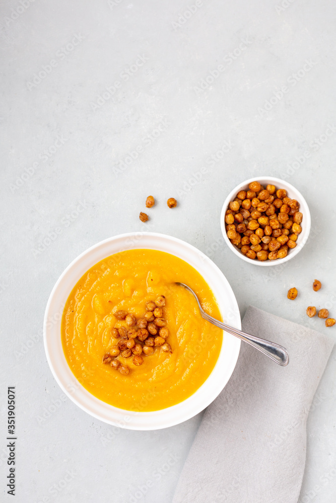 Homemade Butternut Squash Soup in White Bowl on Gray background; Roasted Chickpea Garnish Homemade Butternut Squash Soup in White Bowl on Gray background; Roasted Chickpea Garnish