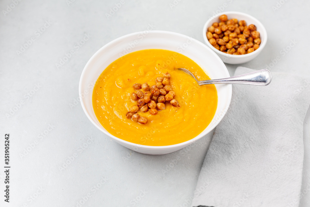 Homemade Butternut Squash Soup in White Bowl on Gray background; Roasted Chickpea Garnish Homemade Butternut Squash Soup in White Bowl on Gray background; Roasted Chickpea Garnish