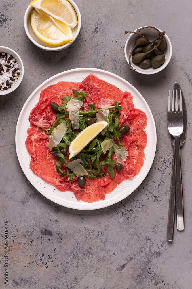 Marbled beef carpaccio with arugula, capers, lemon and parmesan cheese Marbled beef carpaccio with arugula, capers, lemon and parmesan cheese