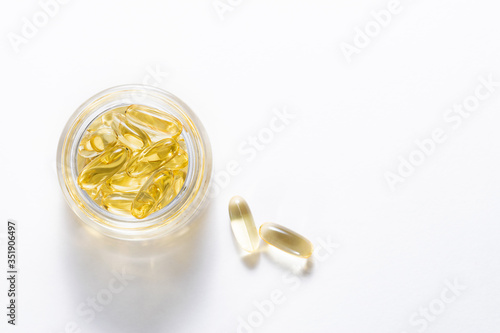 Vitamin D capsules in glass jar on white background top view. Copy space for your design. Healthy lifestyle concept.