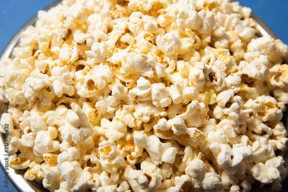 Popcorn in a plate close-up. Blue background Popcorn in a plate close-up. Blue background