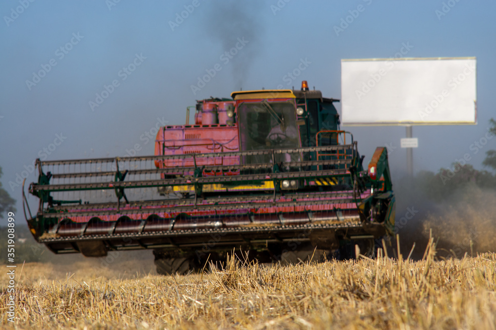 Obraz premium Combine machine is harvesting oats on working