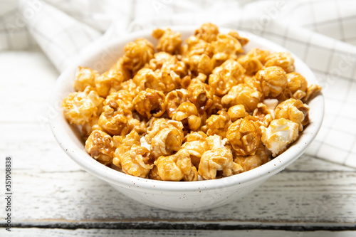 Plate with caramel popcorn on a wooden background. Close-up