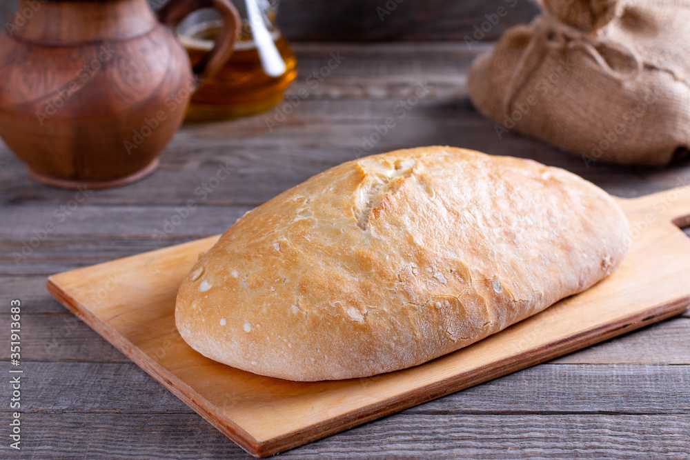 Freshly baked ciabatta bread on wooden cutting board. Ciabatta with ears on the table Freshly baked ciabatta bread on wooden cutting board. Ciabatta with ears on the table