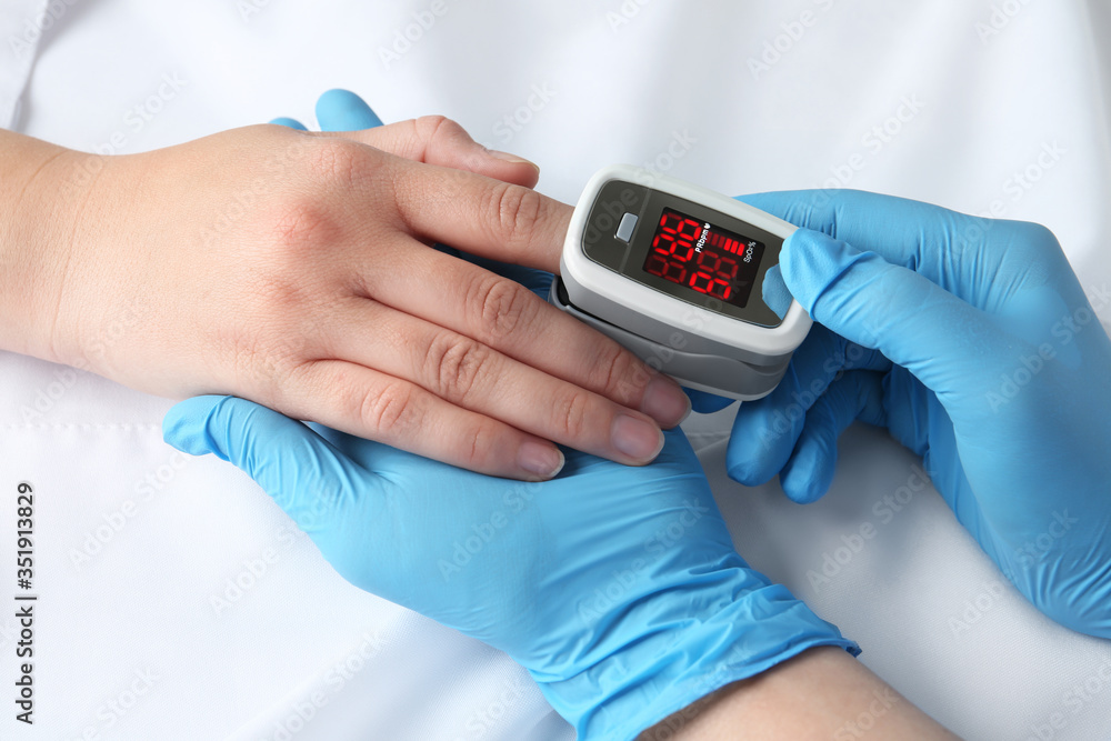 Doctor examining patient with modern fingertip pulse oximeter in bed, closeup - obrazy, fototapety, plakaty 