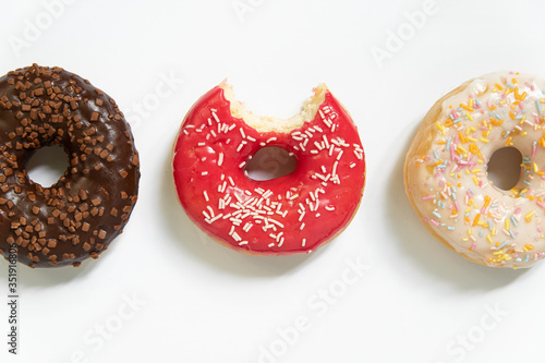 Donut day. Bitten colored donuts with colorful sprinkles on white background. Copy space, close-up