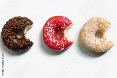 Donut day. Bitten colored donuts with colorful sprinkles on white background. Copy space, close-up