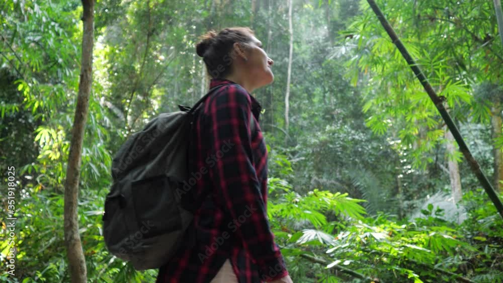 young backpacker woman in checkered shirt walks in breathtaking lush tropical forest slow motion young backpacker woman in checkered shirt walks in breathtaking lush tropical forest slow motion