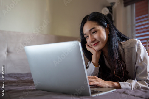 Beautiful Young Asian woman using laptop online chatting with colleagues on bedroom , having a video call on a laptop computer , work from home