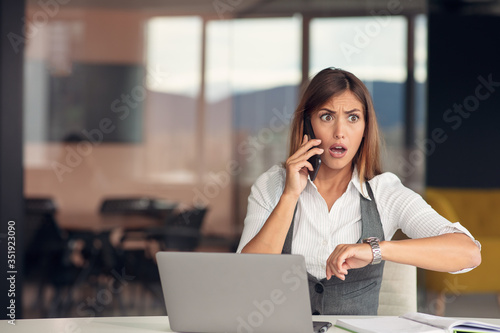 Bored young woman dressed in shirt sitting at her workplace
