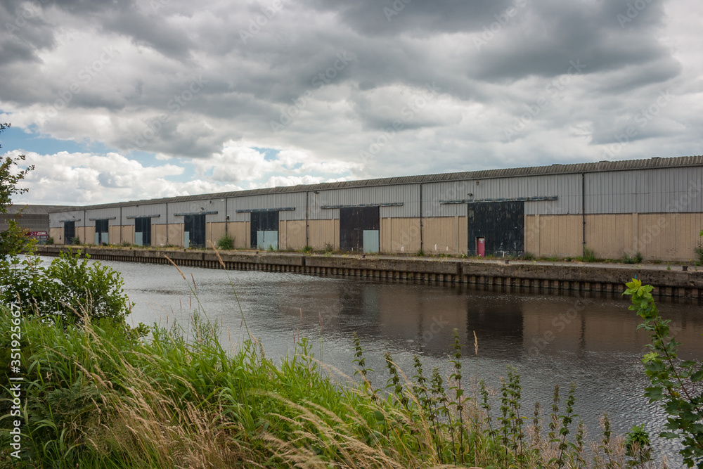 Naklejka premium Old commercial industrial building along a canal on a cloudy day