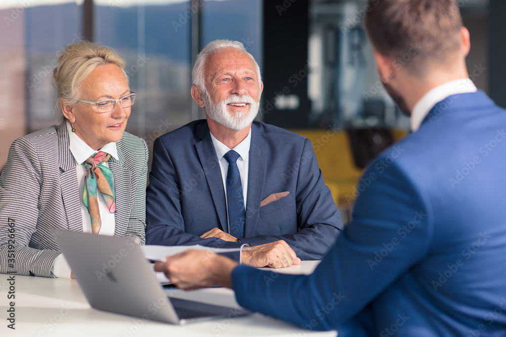 Positive aged couple consulting with insurance agent Positive aged couple consulting with insurance agent