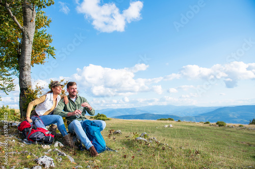 Young couple drinking water while resting on the rock during the travel in the mountains