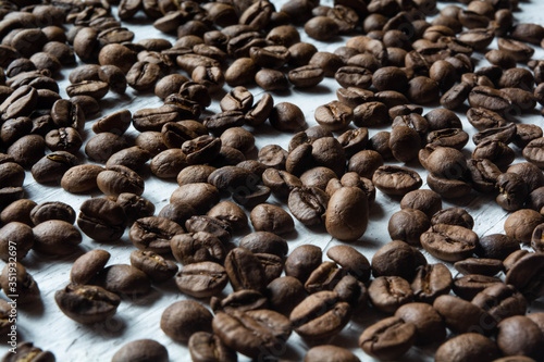Roasted coffee beans scattered on a white surface