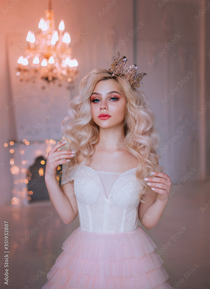 beauty woman fantasy queen. fashion girl model posing image of princess.  Blonde long wavy hair. Royal vintage gold crown. Carnival costume. Natural  makeup pink lips blue eyes. chandelier bright light Stock Photo
