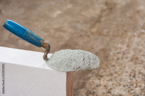 Cement powder or mortar with  trowel put on the Lightweight Concrete brick for construction work..