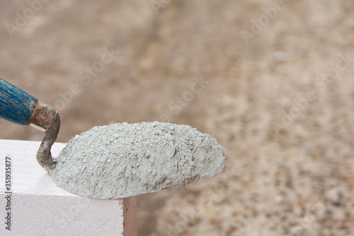 Cement powder or mortar with  trowel put on the Lightweight Concrete brick for construction work..