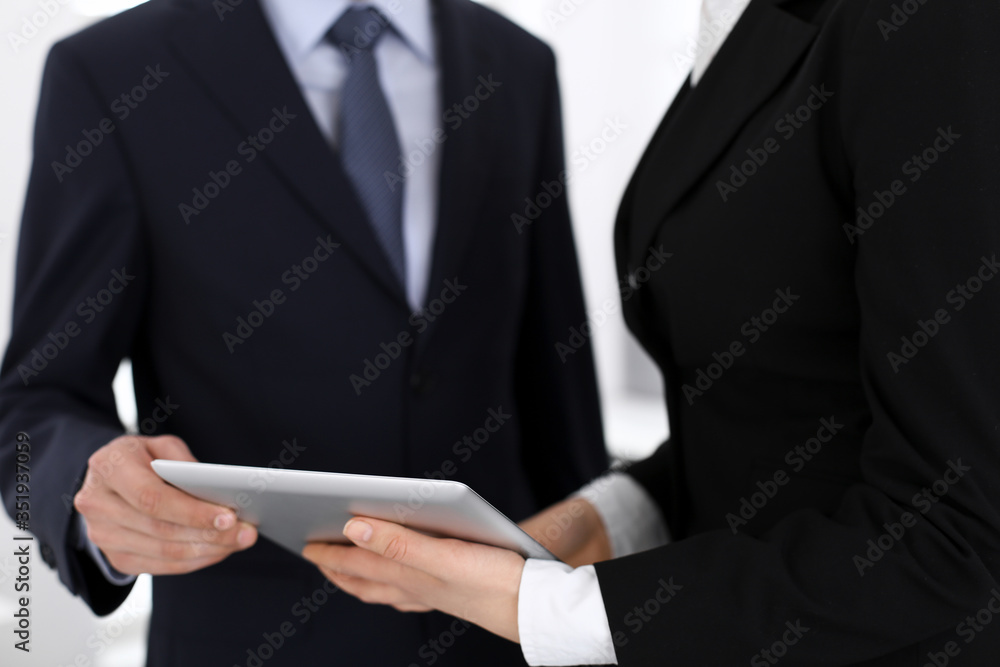 Businessman and woman using tablet computer for discussing questions in office. Partners or colleagues at meeting. Business cooperation concept Businessman and woman using tablet computer for discussing questions in office. Partners or colleagues at meeting. Business cooperation concept
