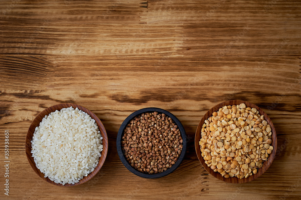 Useful food. The evils and the legumes. Buckwheat, rice, peas in flats on a wooden background. Simple and healthy food. Useful food. The evils and the legumes. Buckwheat, rice, peas in flats on a wooden background. Simple and healthy food.