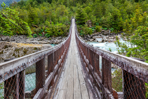 Wooden bridge over Ventisquero River on trail to Glacier, near the village of Puyuhuapi, Chile photo