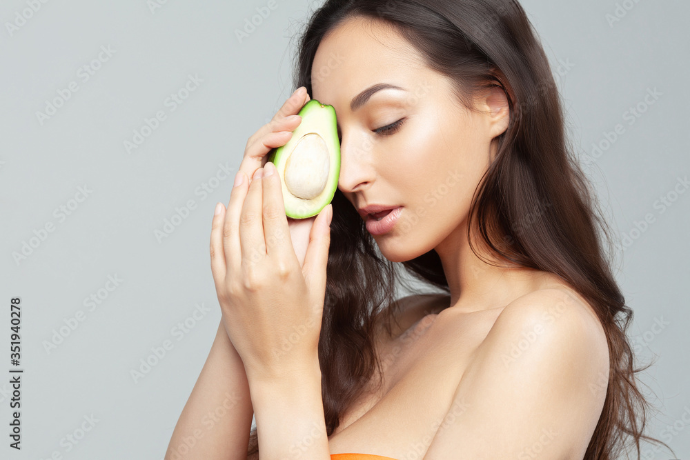Young beautiful woman with avocado closeup Young beautiful woman with avocado closeup