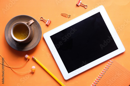 Top view of digital tablet with screen on orange background 