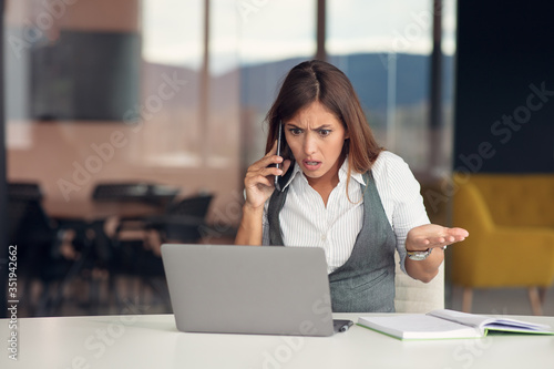 Bored young woman dressed in shirt sitting at her workplace