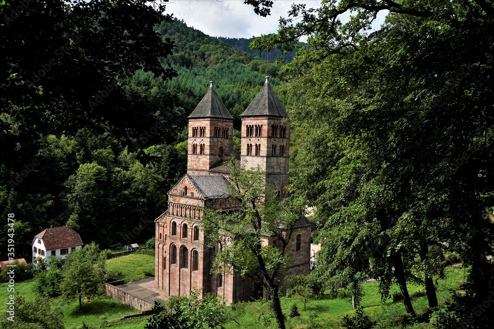Murbach Abbey hidden behind trees with town hall of Murbach Murbach Abbey hidden behind trees with town hall of Murbach