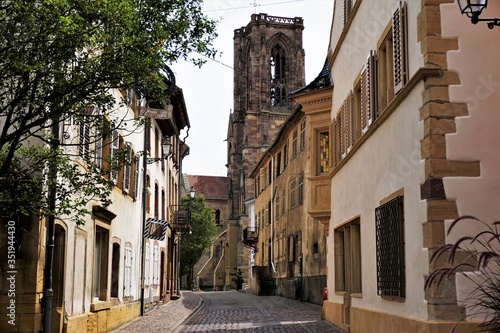 Beautiful street in the village of Rouffach with cobblestone street, residential houses and the Assumption Church