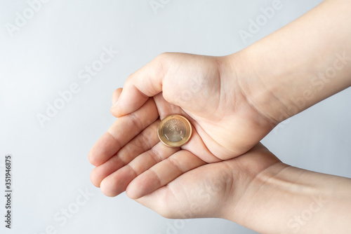 Obraz na płótnie Finance crisis after coronavirus COVID19. Closeup child's hands holding One Euro coin isolated on white background, human hands and saving money concept. w salonie