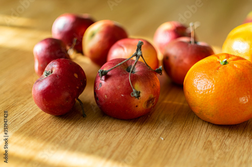 Bright juicy fruits, natural and natural fruits with damage. Red apples and tangerines on a modern brown light table
