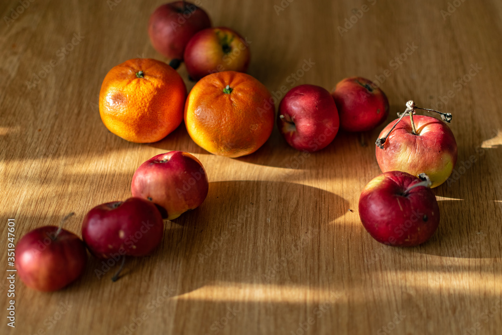 Bright juicy fruits, natural and natural fruits with damage. Red apples and tangerines on a modern brown light table Bright juicy fruits, natural and natural fruits with damage. Red apples and tangerines on a modern brown light table