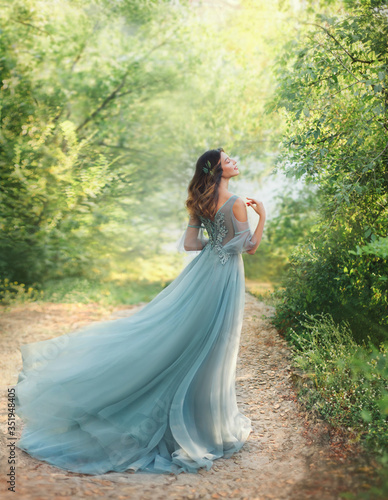 Valokuva fairy tale princess in light summer blue, turquoise dress standing in park