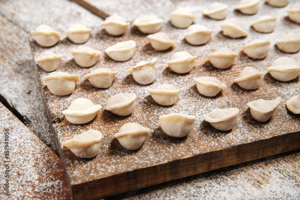 Semi-finished pelmeni dumplings on wooden board Semi-finished pelmeni dumplings on wooden board