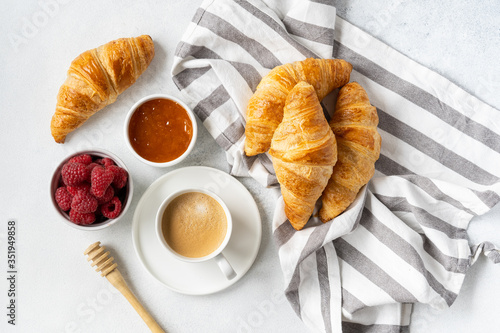 Freshly baked croissants with berries, homemade jam and aromatic coffee for Breakfast on a grey table, top view. Concept of healthy and delicious food.