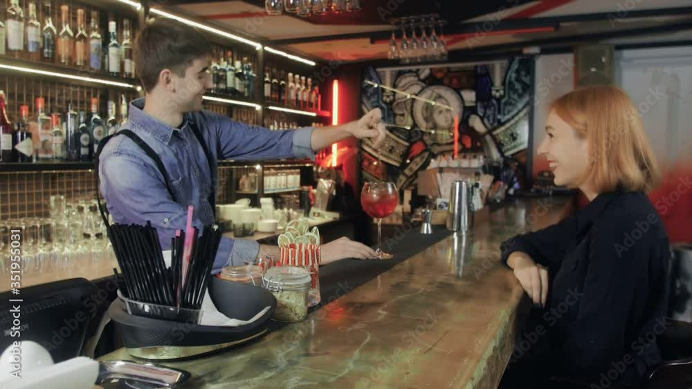 Attractive woman being served cocktails at the bar. Bartender making cocktail to guest. Attractive woman being served cocktails at the bar. Bartender making cocktail to guest.