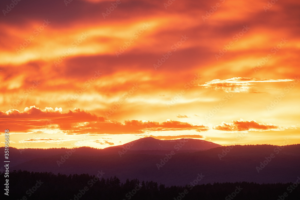 Fototapeta premium Sun setting over hills. Red clouds
