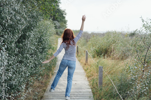 Carefree young woman dancing along a boardwalk