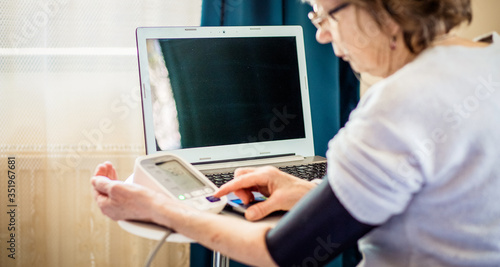 telemedicine concept elderly woman using laptop and taking her blood pressure